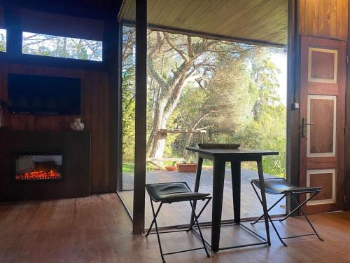 a table and two chairs in a room with a fireplace at Pine Lodge - direct train to Porto in Valongo