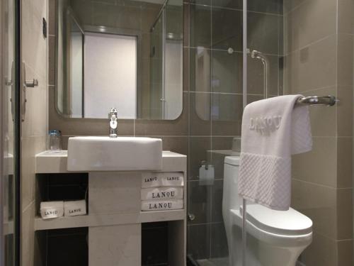 een badkamer met een wastafel, een toilet en een spiegel bij LanOu Hotel Yucheng Yingbin Avenue in Yuncheng