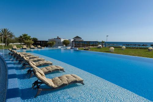 a row of chaise lounges on the side of a swimming pool at Iberostar Selection Kantaoui Bay in Port El Kantaoui