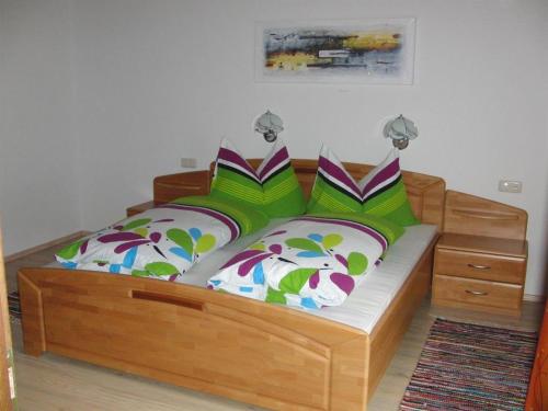 ein Schlafzimmer mit einem Holzbett mit bunten Kissen in der Unterkunft Haus Lärchenhof in Holzgau