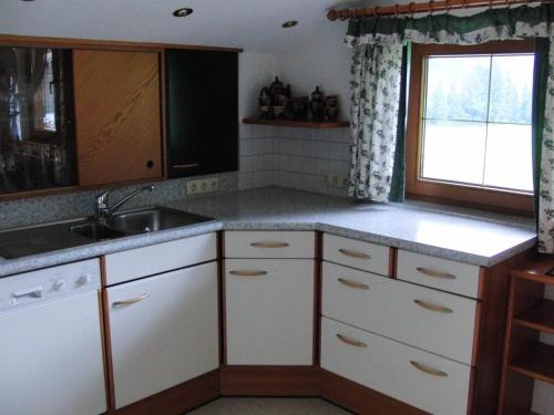 a kitchen with white cabinets and a sink and a window at Haus Lärchenhof in Holzgau