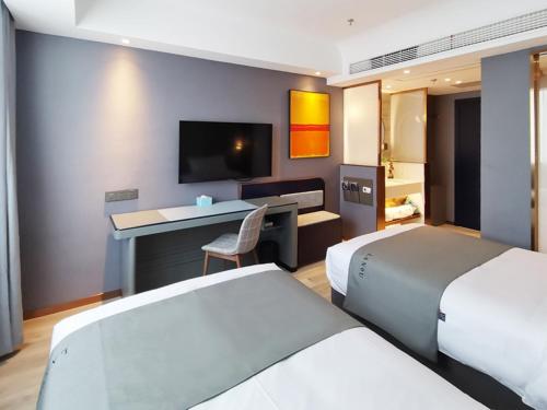 een hotelkamer met 2 bedden, een bureau en een televisie bij LanOu Hotel Taocheng Hengshui Middle School in Hengshui