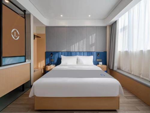 a bedroom with a large white bed and a large window at LanOu Hotel Linyi Railway Station National Fitness Center in Linyi