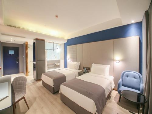 a hotel room with two beds and a desk at LanOu Hotel Zhangye Hexi College Ganquan Park in Zhangye