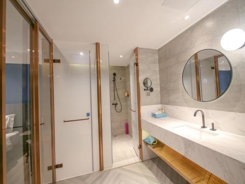 a bathroom with a shower and a sink and a mirror at LanOu Hotel Zhangye Hexi College Ganquan Park in Zhangye