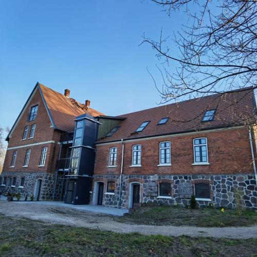a large brick building with a red roof at Inspektorenhaus Dobbin Ferienpension in Linstow