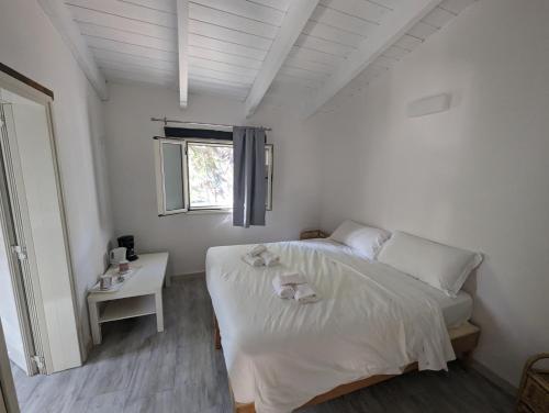 a white bedroom with a bed and a table at Villaggio Camping Torre Del Porticciolo in Porto Conte