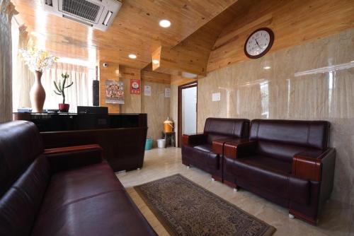 a waiting room with leather couches and a clock at HOTEL KING PARK in Puducherry