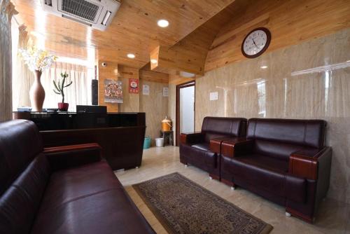 a waiting room with leather couches and a clock at HOTEL KING PARK in Pondicherry