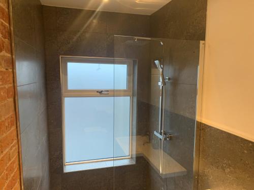 y baño con ducha acristalada y ventana. en Alsager Town Centre Apartment en Alsager