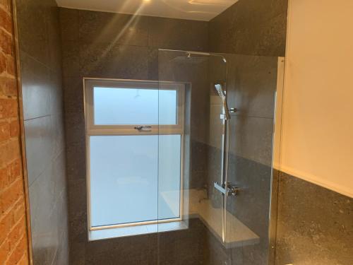 bagno con doccia in vetro e finestra. di Alsager Town Centre Apartment ad Alsager