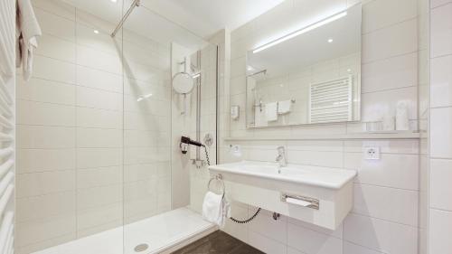 a white bathroom with a sink and a shower at Hotel Schwanen Stuttgart Airport/Messe in Filderstadt