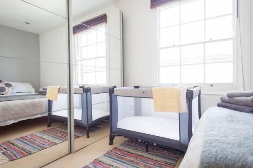 1 Schlafzimmer mit 2 Betten und einem Spiegel in der Unterkunft NAVAL COTTAGE IN THE HEART OF ROYAL GREENWICH in London