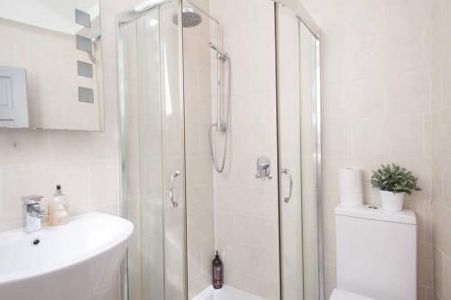 ein weißes Bad mit einer Dusche und einem Waschbecken in der Unterkunft NAVAL COTTAGE IN THE HEART OF ROYAL GREENWICH in London