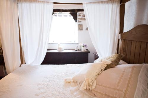 a bedroom with a bed with white curtains and a window at Freelandros Villa in Nardodipace