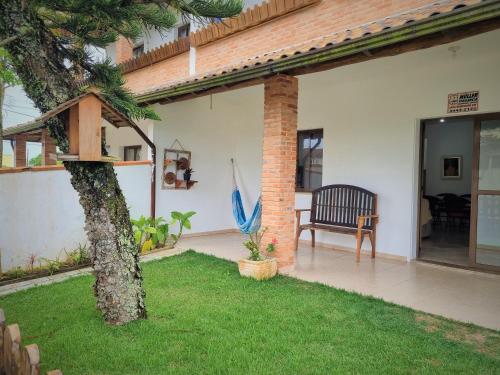 伊塔波阿的住宿－Casa Conforto! A sua casa de praia em Itapoá - SC，一个带树、椅子和遮阳伞的庭院