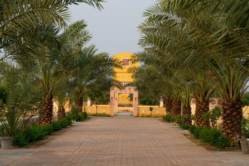 a hallway with palm trees in front of a yellow building at Anand Bagh Resort & Spa by Ananta in Sālāsar