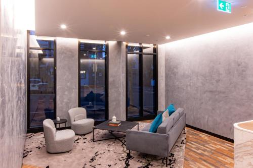a living room with a couch and chairs and windows at The Marker Apartments Melbourne in Melbourne