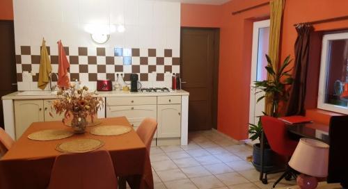 une cuisine avec une table et une cuisine aux murs orange dans l'établissement Petit patio en centre ville, à Nîmes