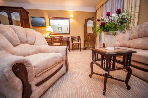 a living room with a couch and a table with flowers at SPA Hotel Splendor in Lubenia