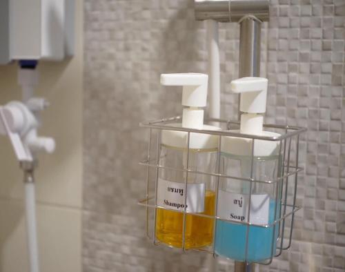 a rack of soap dispensers in a bathroom at Thezen Hotel in Yasothon