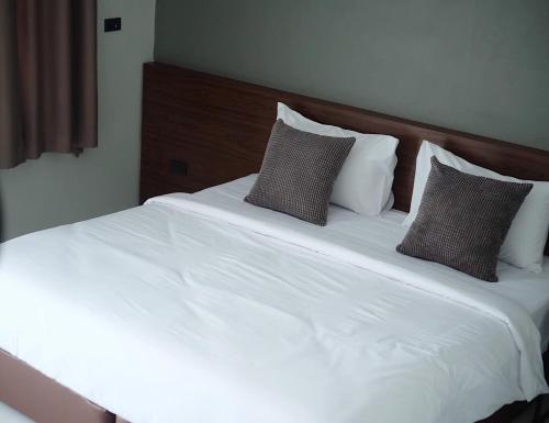 Una cama con sábanas blancas y almohadas. en Thezen Hotel, en Yasothon