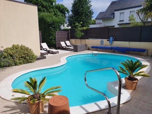 a swimming pool with two palm trees next to a house at Maison d’hôtes du Clos de Kério in Guidel