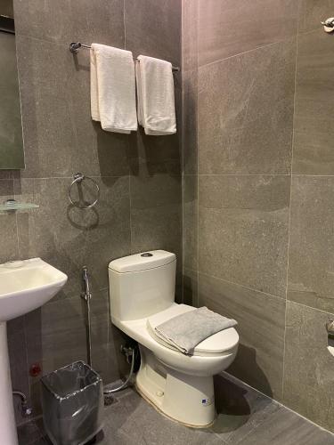 a bathroom with a toilet and a sink and towels at Solace Hotel in Manila
