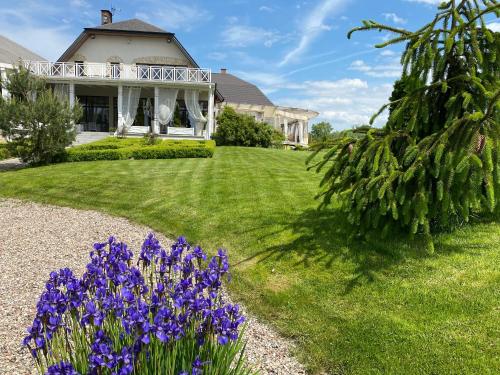 ein Haus mit lila Blumen im Hof in der Unterkunft Hotel-Przystań in Kikół