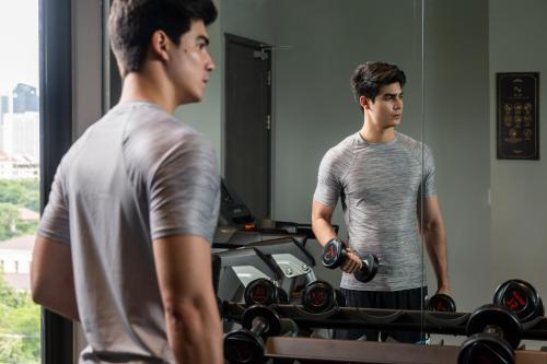 two men standing in a gym with weights at The Quartier Hotel Phromphong - Thonglor in Bangkok