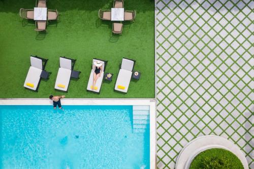 eine Aussicht auf einen Pool mit einem Mann und einer Frau in der Unterkunft The Quartier Hotel Phromphong - Thonglor by Compass Hospitality in Bangkok