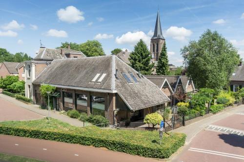 a house with a roof on a street with a church at B&B aan de Koningsmuur in Dieren