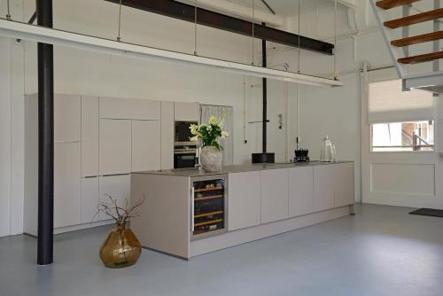 a kitchen with white cabinets and a vase of flowers at B&B aan de Koningsmuur in Dieren
