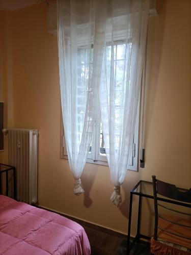a bedroom with a window with white curtains at La casa di Laura in Bologna