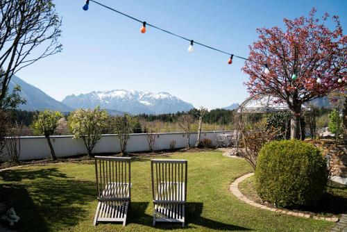 zwei Stühle in einem Hof mit Bergen im Hintergrund in der Unterkunft Best Western Hotel am Walserberg in Wals