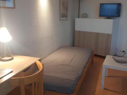 a small room with a bed and a desk with a lamp at Appartement Villard-de-Lans, 2 pièces, 6 personnes - FR-1-515-3 in Villard-de-Lans