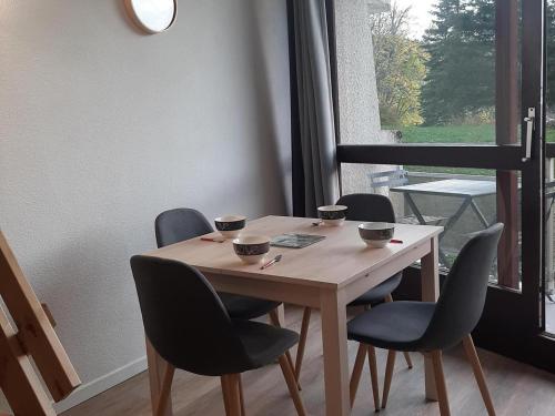 - une table en bois avec des chaises et des tasses dans l'établissement Appartement rénové au pied des pistes, balcon sud, commerces à proximité, parfait pour 4 personnes - FR-1-515-110, à Villard-de-Lans