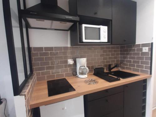 une petite cuisine avec un comptoir et un micro-ondes dans l'établissement Appartement rénové au pied des pistes, balcon sud, commerces à proximité, parfait pour 4 personnes - FR-1-515-110, à Villard-de-Lans