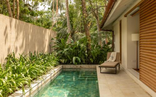 uma piscina com uma cadeira ao lado de uma casa em Kurulu Bay em Ahangama