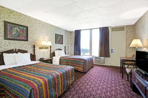 a hotel room with two beds and a television at Days Inn by Wyndham Parsippany in Parsippany