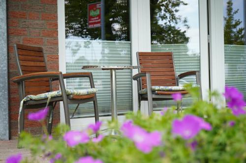 trzy krzesła i stół na ganku z fioletowymi kwiatami w obiekcie Ferienwohnungen Hafenresidenz Alter Speicher Lauterbach w mieście Putbus