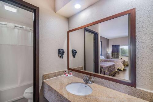 a bathroom with a sink and a mirror and a bed at Super 8 by Wyndham Columbia in Columbia