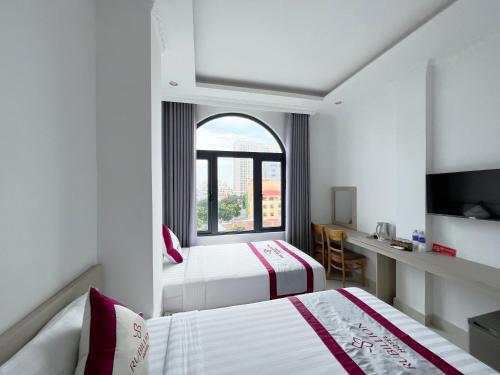 een hotelkamer met 2 bedden en een raam bij Rubillion Hotel - 5-Min Walking to Back Beach in Vung Tau