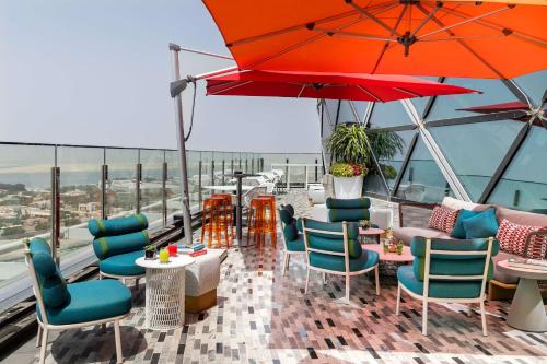 a patio with tables and chairs and a red umbrella at Andaz Capital Gate Abu Dhabi - a concept by Hyatt in Abu Dhabi
