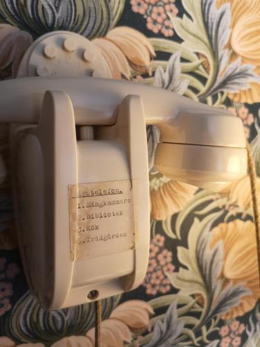 a telephone hanging on a wall with a floral wallpaper at Disponentparken Café och Bed & Breakfast in Grängesberg
