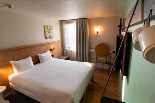 Habitación de hotel con cama blanca y ventana en Greet Hotel Colmar, en Colmar