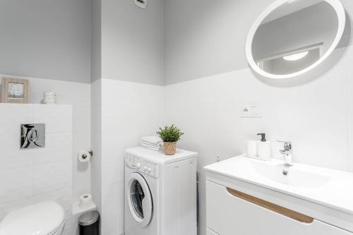 a white bathroom with a washing machine and a sink at Chill Apartments Mokotów Business Center in Warsaw