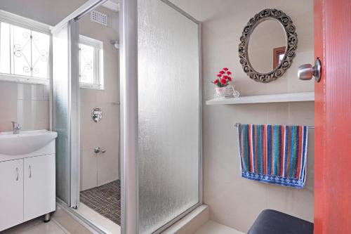 a bathroom with a shower and a sink and a mirror at 25 Jacaranda Lodge & Backpackers in Pinetown