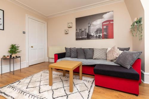 a living room with a red couch and a table at Modern Aberdeen City apartment free parking in Aberdeen