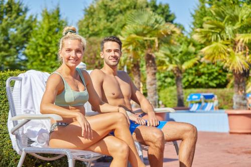a man and a woman sitting on a chair by a pool at Appartement-Haus Blumenhof in Bad Griesbach
